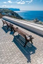 Empty benches on sea shore in a park. Sea view from mountain. Travel, relax or loneliness concept. Wooden bench on open space