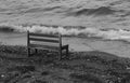 An empty bench seat on beach across waves