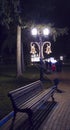 Empty bench under lantern in evening park. Night lights illuminate the path