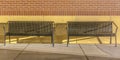 Empty benches against a brick wall on a sunny day Royalty Free Stock Photo