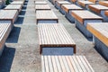 Empty benches wooden and concrete surface stand in several rows on the street in the park on the asphalt, nobody is there Royalty Free Stock Photo