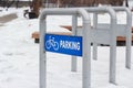 Empty bike parking in snowy public park at cold winter, urban bicycle station in city recreation zone, cloudy weather Royalty Free Stock Photo