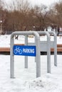 Empty bike parking in snowy public park at cold winter, urban bicycle station in city recreation zone, cloudy weather Royalty Free Stock Photo