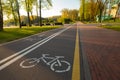 Empty bike path route infrastructure early in the spring sunny morning. No people in the park, green grass, trees and blue sky. Royalty Free Stock Photo