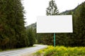 Empty billboard or big board on side of road with green forest and hills on background. Advertising blank, mock up, copy space for