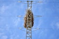 empty bird nest made with branches of trees at the top of an electrical tower of high voltage that conducts electricity to houses Royalty Free Stock Photo