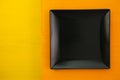 Empty black ceramic dish on over orange and yellow background Royalty Free Stock Photo