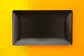 Empty black ceramic dish on over orange and yellow wooden table Royalty Free Stock Photo