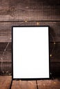 Empty black frame with twinkle light on aged wooden backgro Royalty Free Stock Photo