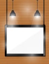 Empty black frames on wooden wall with spotlights.