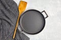 Empty black iron empty frying pan, wooden spatula and gray kitchen towel on a gray concrete background Royalty Free Stock Photo