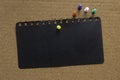 An empty black paper with colorful push pin on a notice cork board. Copy space for text, logo Royalty Free Stock Photo