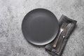 Black plate, fork and knife on grey stone table. Elegance table place setting. Copy space. View from above. Royalty Free Stock Photo