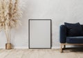 Empty black poster frame mockup on the wooden parquet near gray concrete wall in modern interior design scene with blue sofa, vase Royalty Free Stock Photo
