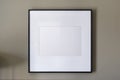 Empty black square frame, white canvas, mock up, on a gray wall, bedroom, template front angle