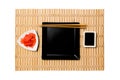 Empty black square plate with chopsticks for sushi, ginger and soy sauce on yellow bamboo mat background. Top view with copy space Royalty Free Stock Photo