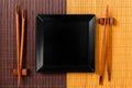 Empty black square slate plate with chopsticks for sushi on wooden background. Top view with copy space Royalty Free Stock Photo