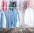 Empty wooden surface and clean clothes on hangers in dry-cleaning, space for text Royalty Free Stock Photo