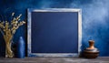 Empty blackboard with vase and dried flowers in a glass on dark blue background