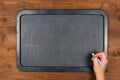 Empty blackboard on wooden table with hand with chalk