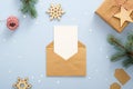 Empty blank card in kraft paper envelope on pastel blue background decorated with confetti star, gift box, wooden snowflakes, fir Royalty Free Stock Photo