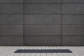 Empty and blank foldable black yoga mat on grey sidewalk near empty street outdoor in front of grungy concrete textured wall with