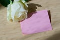 Empty blank pink paper note and white rose on wood table Royalty Free Stock Photo