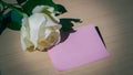 Empty blank pink paper note and white rose on wood table Royalty Free Stock Photo