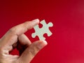 Empty blank space of a piece of puzzle jigsaw element in man's hand  on red background, minimal style. Royalty Free Stock Photo