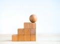 Empty blank wooden cube blocks build as a steps with the sphere one on top, isolated on wood desk on white background. Royalty Free Stock Photo