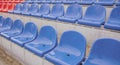 Empty bleacher in sports stadium in rainy weather. Colored wet seats in street stadium. It's raining. Close up.