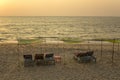 Empty blue beach beds under green yellow canopies on yellow sand against the sea in the evening sunset Royalty Free Stock Photo