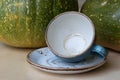 An empty blue coffee cup lies tilted on a saucer