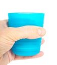 Empty blue plastic glass, held in a male persons hand