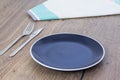 Empty blue plate, cloth napkin and cutlery set on wooden table. Royalty Free Stock Photo