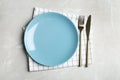 Empty blue plate with cutlery and napkin on grey marble table, flat lay Royalty Free Stock Photo