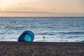 Empty blue tent on the beach. Sunset on the sea coast. Camping on the shore of the ocean.