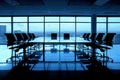 An empty boardroom table with chairs arranged around,against backdrop of floortoceiling windows Royalty Free Stock Photo