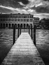 an empty boardwalk leading to a city over water in front of a boat dock