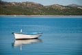 Empty boat with seagull with shore and hills in the background