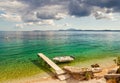 Empty boat standing at wooden pier under bright sunlight Royalty Free Stock Photo