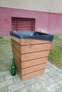 Empty bottle next to a wooden trash can