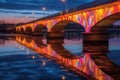 empty bridge with colorful lights reflected on water