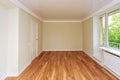 Empty bright room with a wooden floor and light wallpaper. The apartment is after renovation. Royalty Free Stock Photo