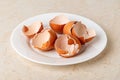 Empty broken eggshells on a white plate over kitchen table. Halved shells of brown chicken eggs close-up. Food product high in