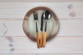 Empty brown ceramic plate with a knife, fork, spoon on an old wooden table made of boards with a natural pattern, close-up Royalty Free Stock Photo