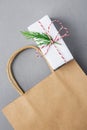 Empty Brown Craft Paper Bag White Christmas Gift Box with Red Ribbon Green Juniper Twig on Gray Background. Sales Discount Shoppin Royalty Free Stock Photo