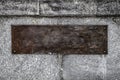 An empty brown rusty steel plate bolted with four round bolts to a gray granite wall. Template for design. Vintage background with