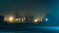 An empty car park with street lights glowing in the distance on a mysterious moody, foggy atmospheric winters night