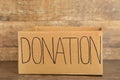 Empty cardboard donation box on brown background. Inscription donation